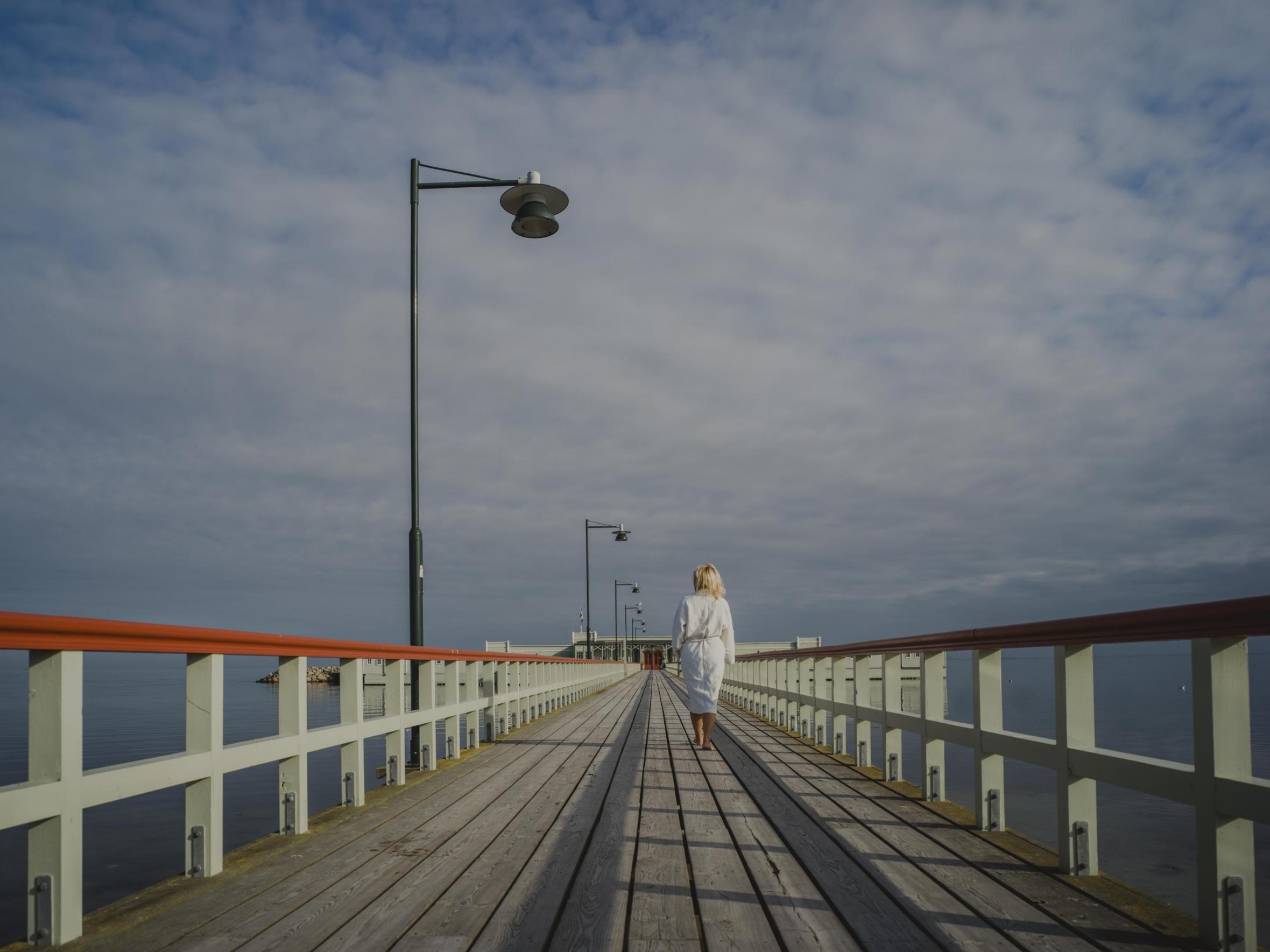 En kvinna går på bryggan mot Ribersborgs kallbadhus en sommardag 